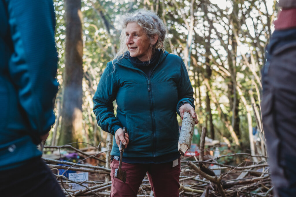 Photo shows woman holding wood and engagaing in woodland activites