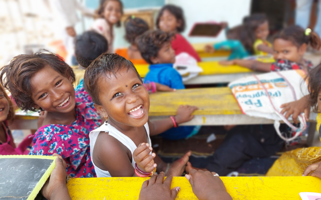 Double the difference donation impact - indian child in classroom looking back at camera and smiling