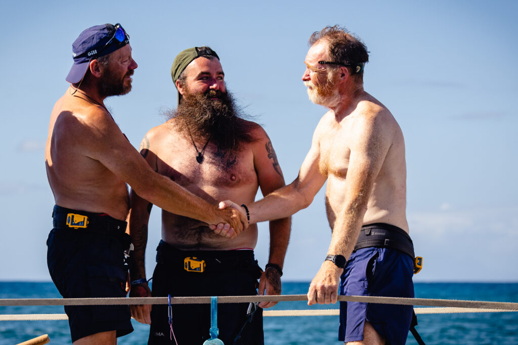 Double the difference donation impact - three men on a boat, talking whilst two clasp hands